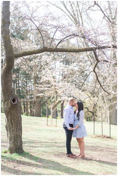 an engaged couple standing under a tree in the park