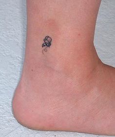 a small tattoo on the ankle of a woman's foot with a skull and crossbone