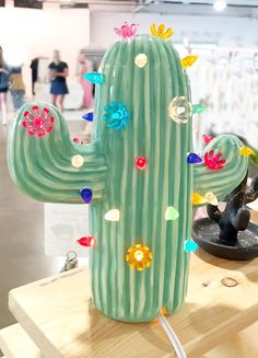 a cactus with many colorful flowers on it sitting on a table in front of people