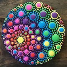 a colorful painting on a wooden surface with circles and dots in the center, as well as colors