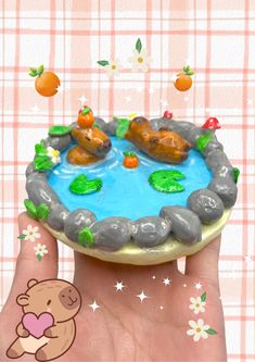 a hand holding a small cake with animals on it