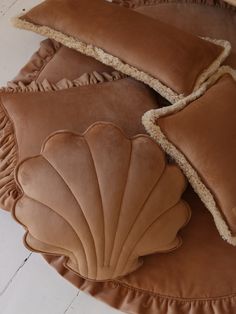 two brown pillows with scalloped edges on top of a round pillow case in the shape of a seashell