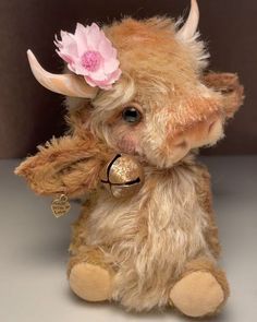 a stuffed cow with a flower on its head and bell around it's neck