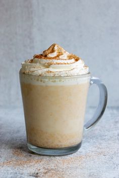 there is a cup with whipped cream in it and cinnamon on the rim, sitting on a table