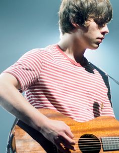 a young man playing an acoustic guitar on stage