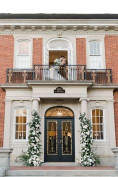 a bride and groom are standing on the balcony of their wedding venue in front of an elegant building