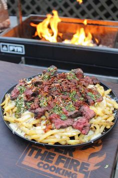 a plate of food sitting on top of a wooden table next to a fire pit