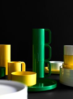 some yellow and green cups are sitting on the table next to each other in front of a black background