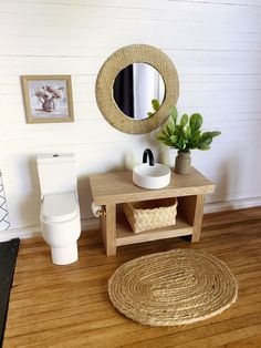 a bathroom with a toilet, sink and mirror on the wall next to a wooden floor