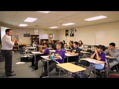 a man standing in front of a class room full of kids sitting at desks