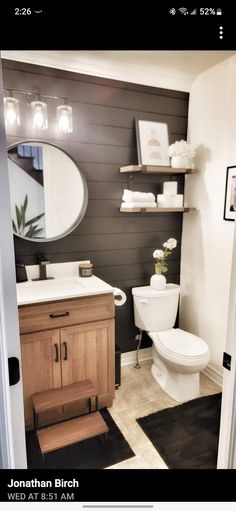 a white toilet sitting in a bathroom next to a wooden sink vanity and open door