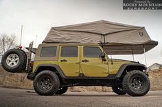 a yellow jeep with a tent on top