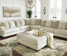 a living room filled with furniture and a chandelier hanging from the ceiling over a rug