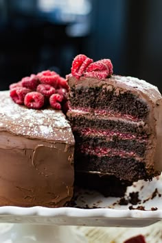 a chocolate cake with raspberries and powdered sugar on top is cut in half