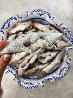 a hand holding a powdered pastry in a blue and white bowl