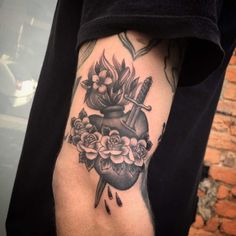 a person with a tattoo on their arm holding a knife and flower arrangement in front of them