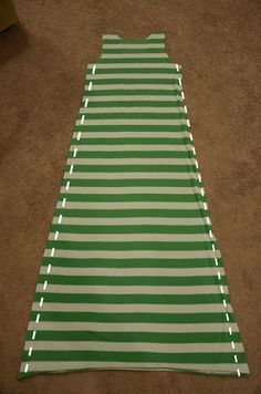 a green and white striped sleeping bag laying on the floor next to a brown carpet