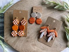 three pairs of orange and white earrings sitting on top of a table