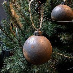 two metal ornaments hanging from a christmas tree