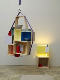 a hanging object made out of wooden boxes and other items on the floor next to a white wall