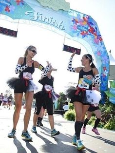 three women in costumes are running at the finish line