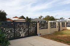 a fence that has trees on it and birds in the tree, is next to a house