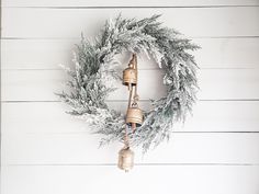 a christmas wreath with bells hanging from it on a white wooden wall next to a fireplace