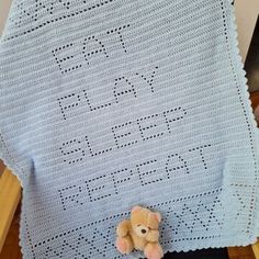 a teddy bear sitting on top of a crocheted blanket