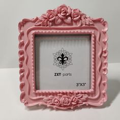 a pink frame with flowers and a fleur de lis on the front is shown