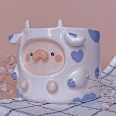 a blue and white ceramic pig mug sitting on a checkered table cloth next to flowers