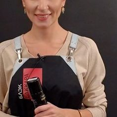 a woman is holding an electronic device in her right hand and smiling at the camera