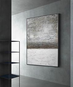 an abstract painting hangs on the wall next to a bookshelf and shelving unit