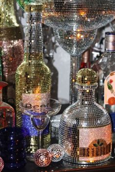 there are many different bottles and glasses on the table with disco balls all around them