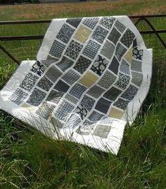 a patchwork quilt sitting on top of a metal bed frame in the middle of a field