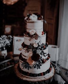 a three tiered wedding cake with flowers on the top and bottom is sitting on a table