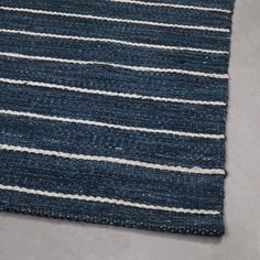 a blue and white striped rug is laying on top of the floor next to a gray wall