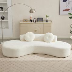 a large white couch sitting on top of a rug in a living room next to a lamp