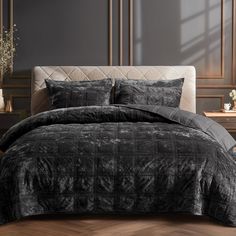 a bed with black comforter and pillows on top of it in a dark room