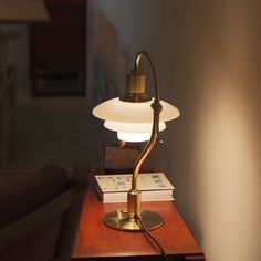 a desk lamp sitting on top of a wooden table next to a book and chair