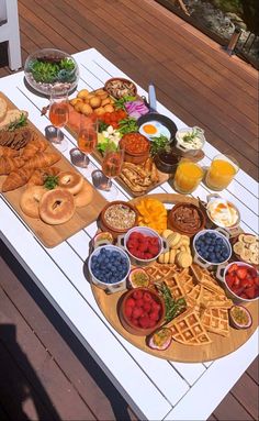 a table filled with different types of food and drinks on top of a wooden deck