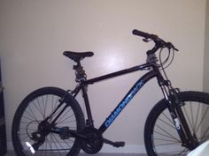 a black and blue bike parked next to a white wall