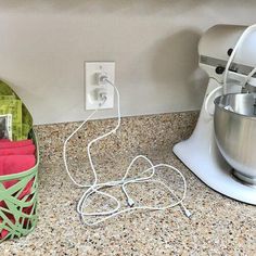 a kitchen counter with an electric mixer and green basket on it, next to a blender