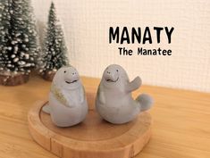 two small plastic ghost figurines sitting on top of a wooden table next to christmas trees