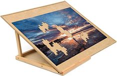 a wooden easel with an image of a cross in the middle and sunset behind it