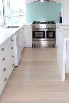 an empty kitchen with white cabinets and stainless steel stove top oven in the center of the room