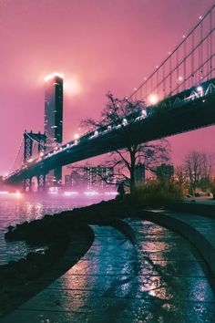 the bridge is lit up at night and it's lights shine brightly over the water