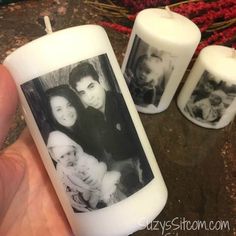 three candles with pictures on them in front of a christmas wreath and two hands holding one candle