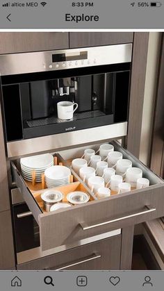 an appliance is open to show the contents in its drawer, including cups and saucers