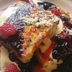 a piece of french toast with berries and cream on the side sitting on a plate