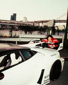 a man sitting on top of a white sports car